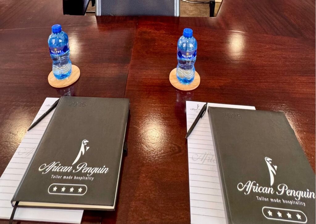 Professional corporate setup at The African Penguin featuring branded stationery and refreshments on a polished boardroom table.